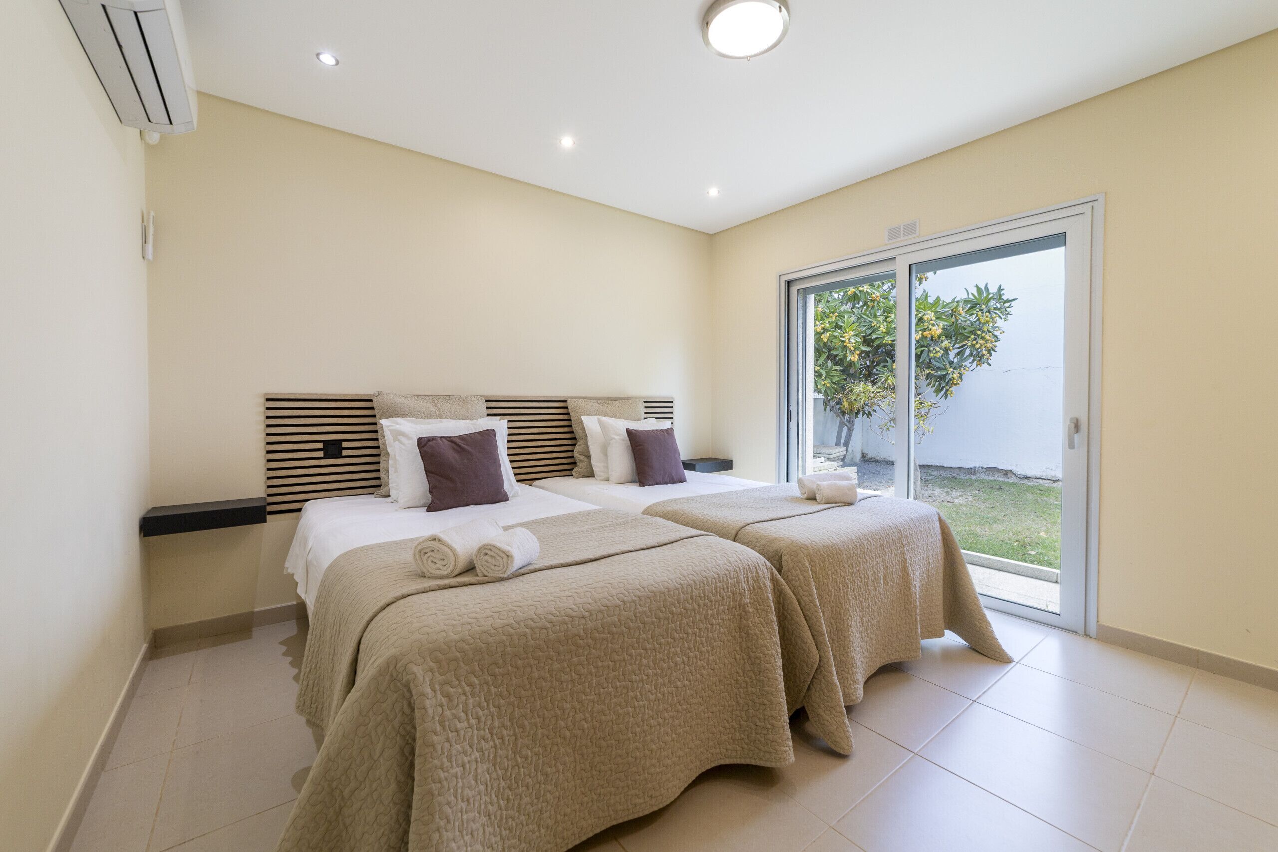 A hotel room with two beds, a sliding glass door to the outside, and a ceiling light.