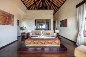 A spacious hotel room with a large bed, a potted plant, and artwork on the walls. - Luxury Villa with private driver +welcome dinner, ocean views and amazing sunset (South Kuta)