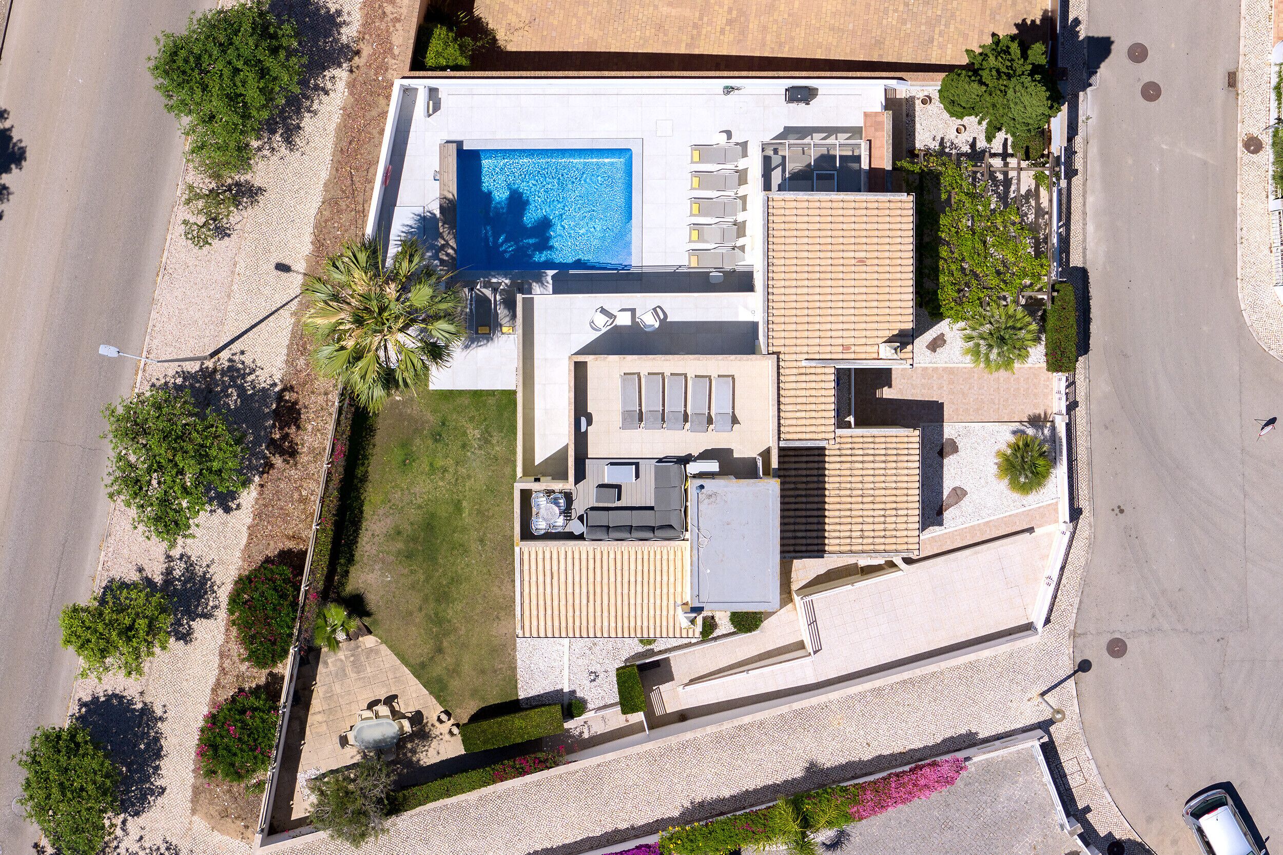 An aerial view of a modern house with a swimming pool, multiple balconies, and a well-maintained garden.