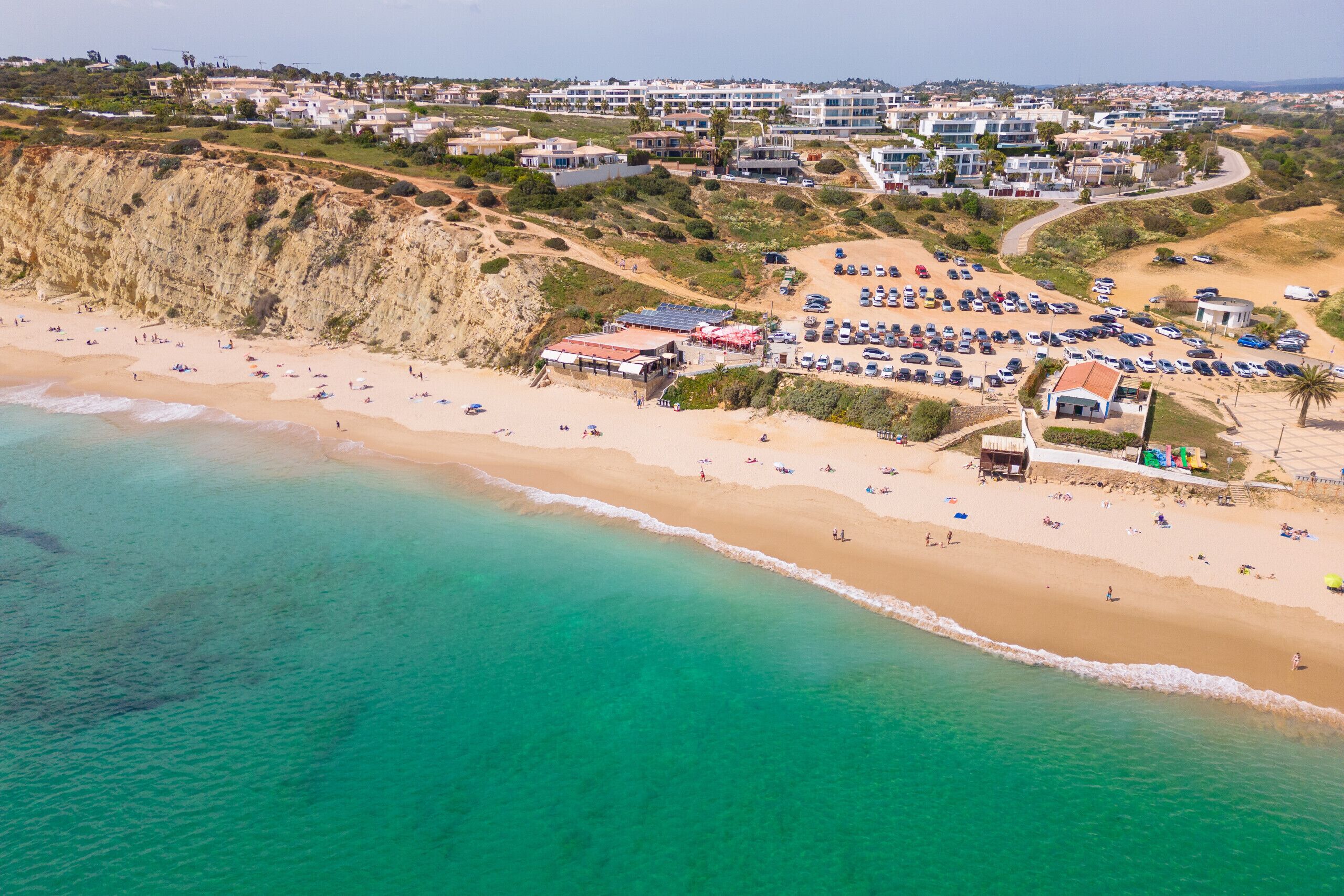 Vista aérea de una zona costera con playa, aparcamiento y edificios.