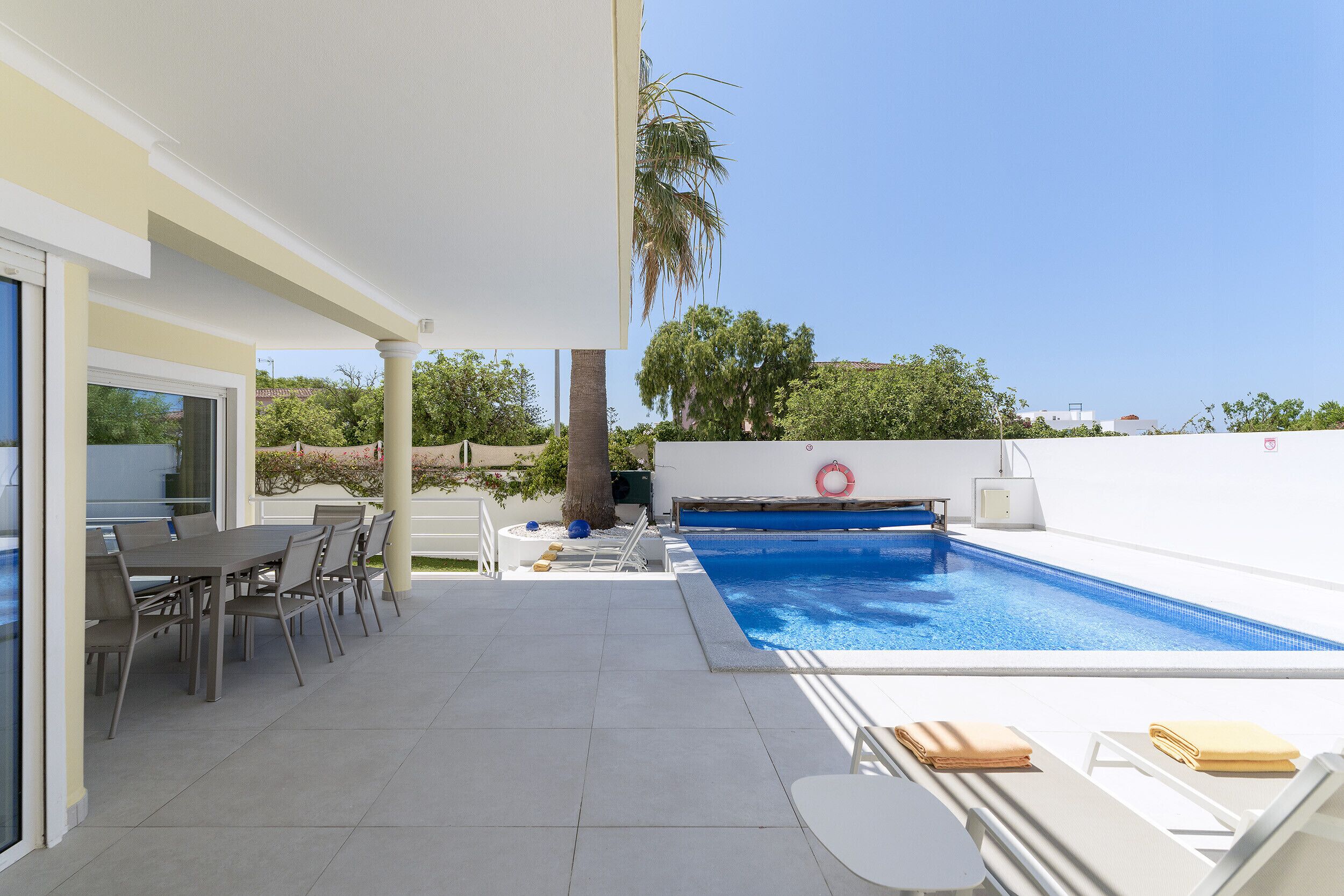 A poolside area with a table and chairs, a small pool, and a lifebuoy.