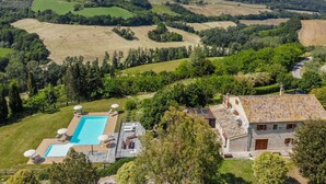Une villa dotée d’une piscine, d’un espace extérieur aménagé et offrant une vue sur des collines verdoyantes et des vignobles.