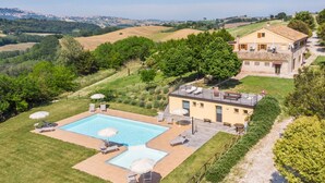 Une villa avec piscine, espace extérieur aménagé et vue sur la campagne.