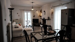 Ein modernes Wohnzimmer mit Sofa, Fernseher, Kamin, Esstisch und Stühlen.
