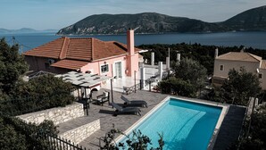 Un espace piscine offrant une vue dégagée sur la mer et les montagnes en arrière-plan.
