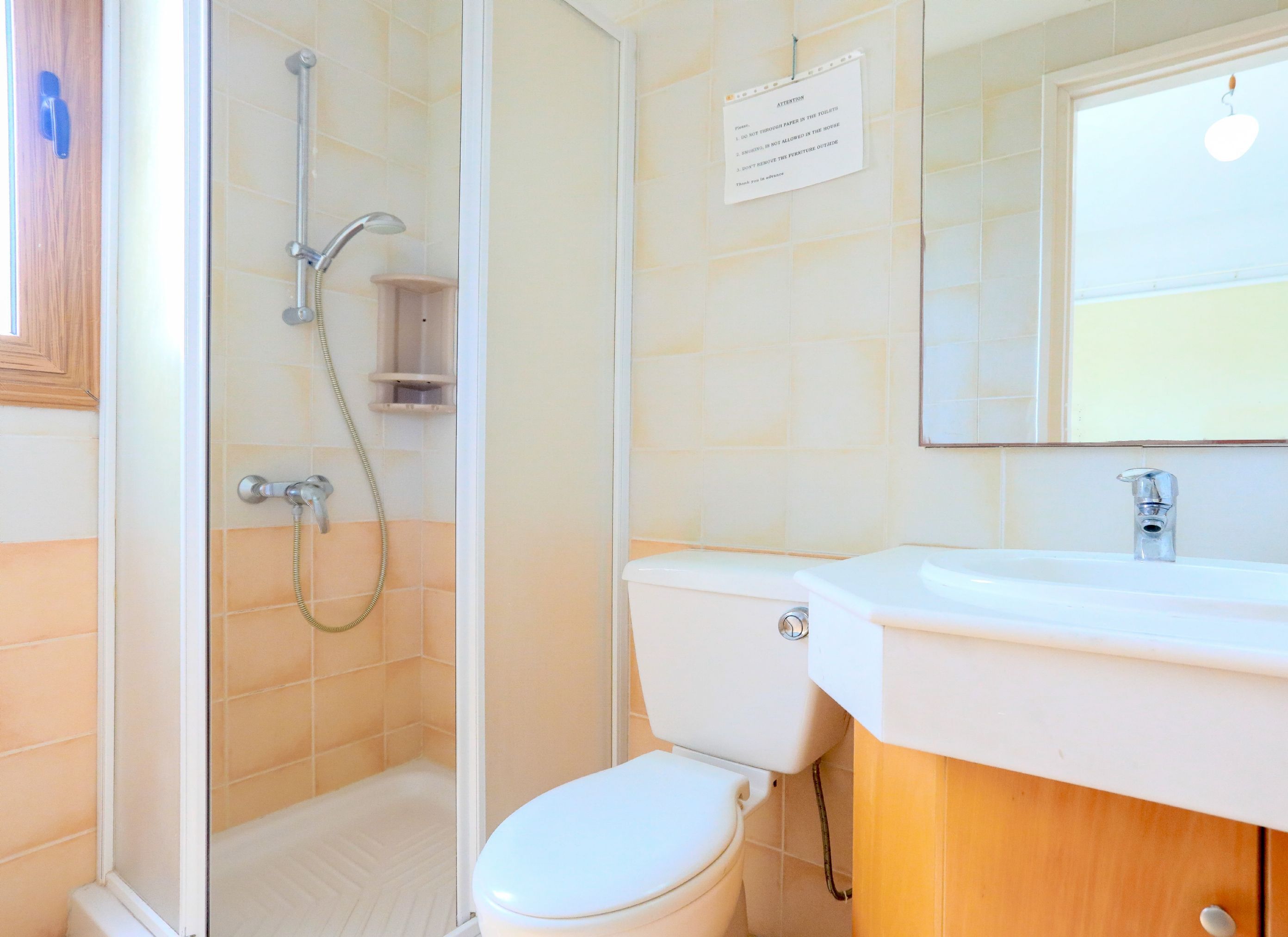 A bathroom with a glass-enclosed shower, a toilet, and a sink with a mirror above.