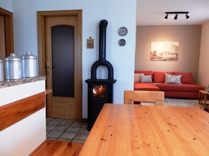 Cozy living space with a central stove, dining table, and comfortable sofa.