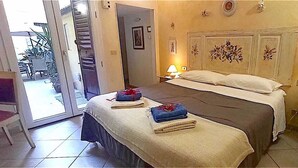 A bedroom with a bed, a nightstand, a lamp, and a door leading to a balcony. - Florence Historic Center | Private Courtyard | Walk to Everything, WIFI, AC (Firenze)
