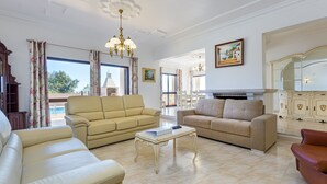A spacious living room with two sofas, a coffee table, and a chandelier.
