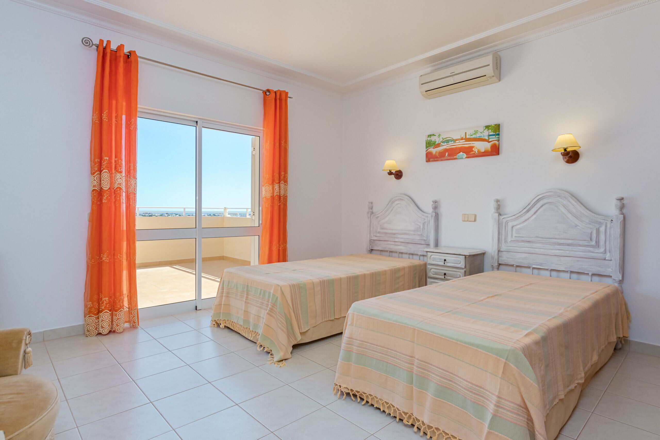 A hotel room with two beds, a balcony, a painting, and a lamp.