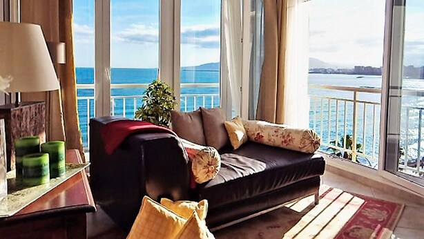 A balcony with a view of the sea, a sofa, a lamp, and a small plant. - Morlaco apartment (Málaga)
