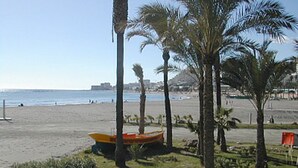 A beach with palm trees, a boat, and a clear sky. - Morlaco apartment (Málaga)
