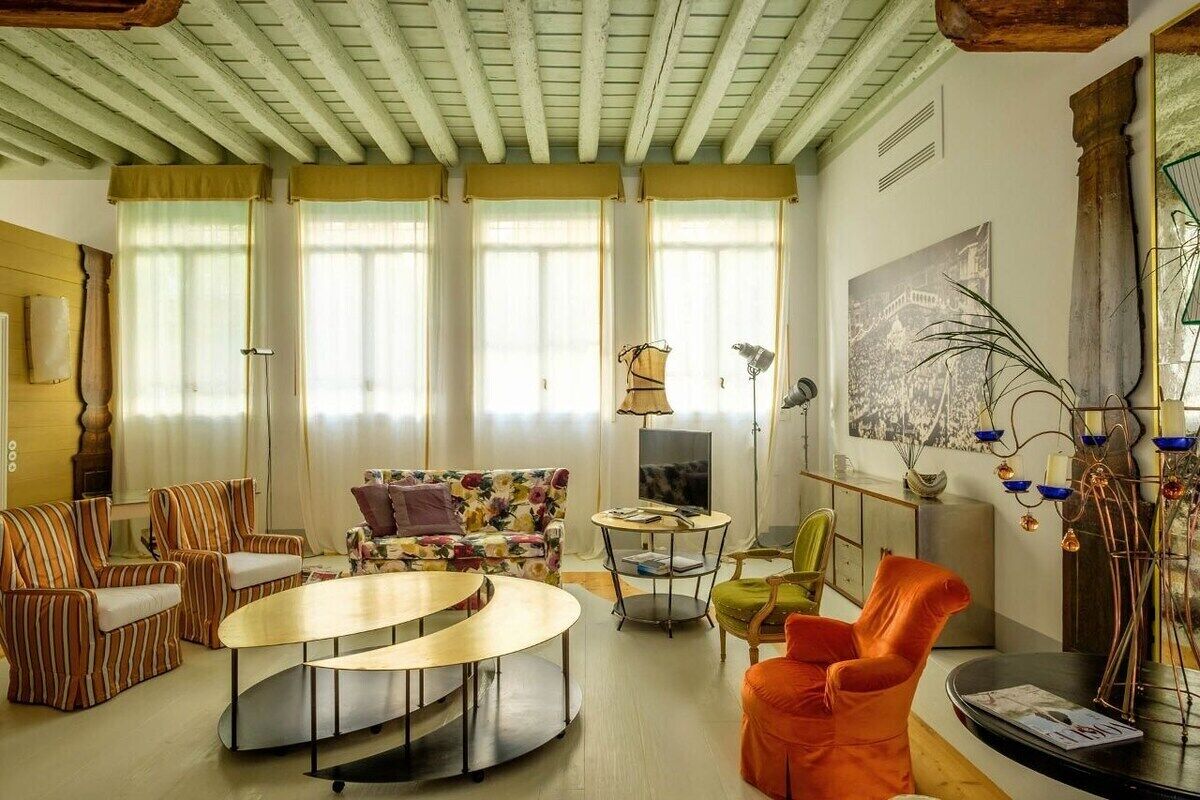 Una sala con sofás a rayas, una mesa de centro redonda y un sofá floral colorido.