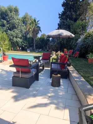 An outdoor patio area with a pool, lounge chairs, and a table with a canopy.