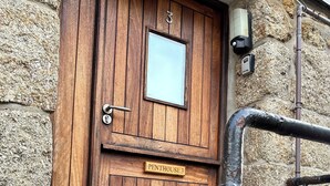 Eine Holztür mit kleinem Fenster, Klingel und einem Schild mit der Aufschrift 'PENTHOUSE 3'.