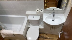 Ein Badezimmer mit Badewanne, Toilette, Waschbecken und Spiegel.