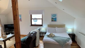 Ein Schlafzimmer mit einem Bett, Nachttischlampen, einem Fernseher, einem Fenster und einem Gemälde.