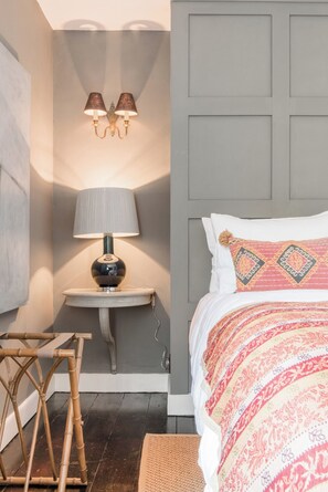 A bedroom with a bed, bedside table, lamp, and a chair.