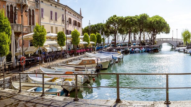 A canal with boats docked, a bridge, and buildings with outdoor seating. - Villa Mimosa Near Desenzano Old Town Apt 2 Parking, A/C, WiFi, Desenzano Del Garda, Italy (Desenzano Del Garda)