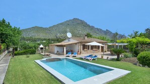 A swimming pool with lounge chairs, a house with a satellite dish, and a mountain in the background. - VILLA  MARGARITA - 15 MIN WALK TO THE BEACH (Puerto Pollensa)