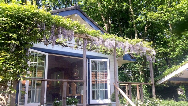 A house with a covered porch, large windows, and a wooden staircase leading to the entrance.