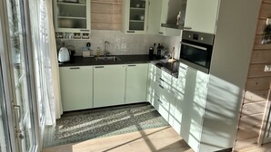 A modern kitchen with light-colored cabinets, a stainless steel sink, and a built-in oven.