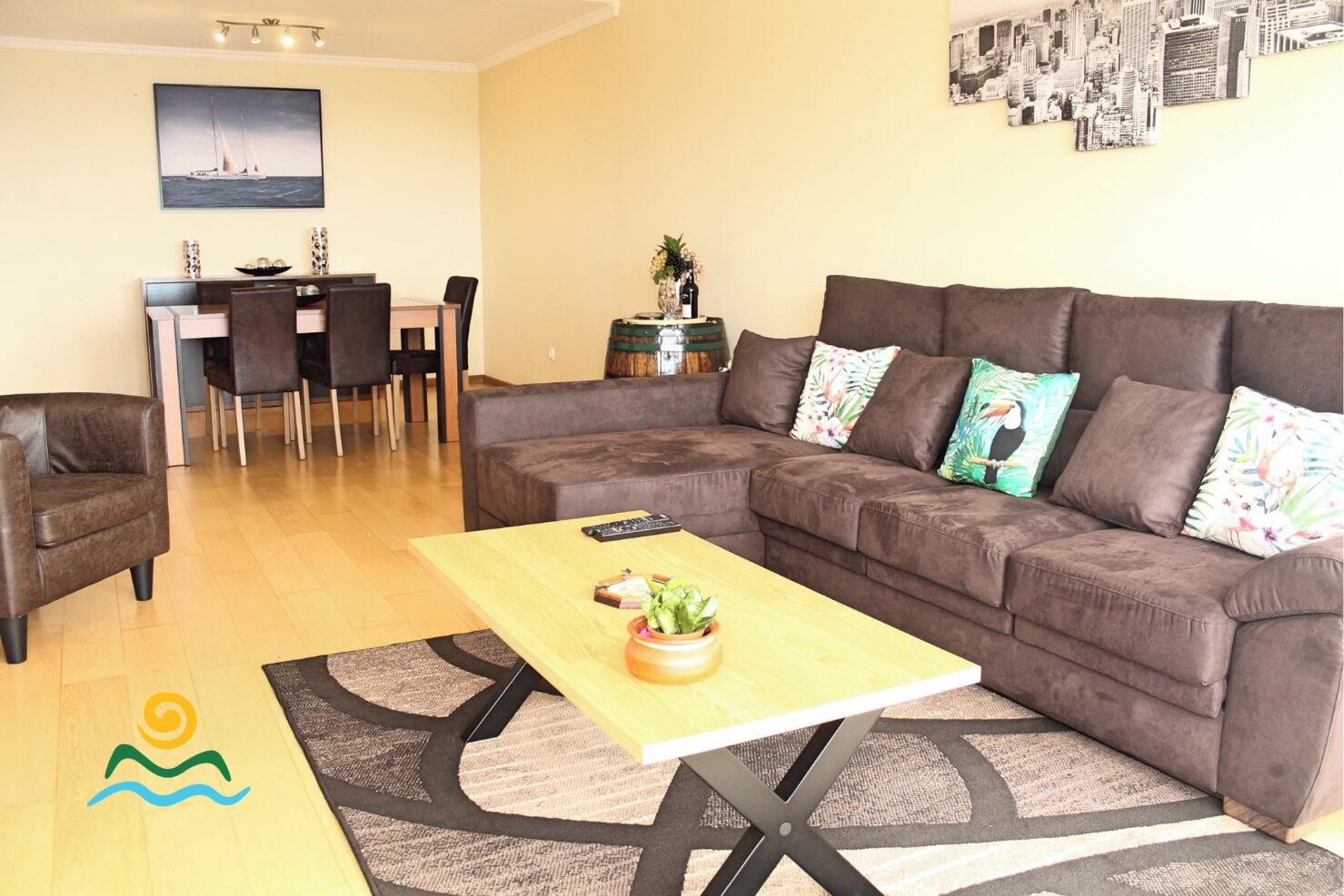 A living room with a brown sofa, a wooden coffee table, and a dining area with chairs and a table.