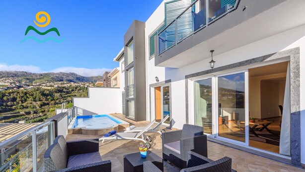A modern outdoor patio with a pool, lounge chairs, and a dining area with a view of the surrounding landscape. - 3-bedroom villa in Calheta, sea-view | Casa Belita (Calheta)