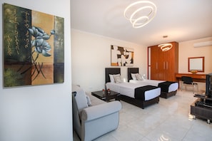 A modern hotel room with two beds, a sofa, a desk, and artwork on the walls. - Countryside Escape w/ Sea View & Ping Pong (Rethymno)