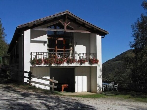 A two-story building with a balcony, a garage door, and a wooden fence. - Toki Ona cottage for 22 people (Navarra)