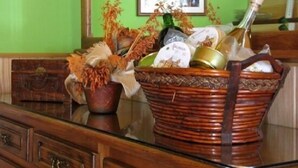 Un mueble de madera con cajones y una mesa con superficie de vidrio que sostiene una cesta de mimbre con varios objetos.