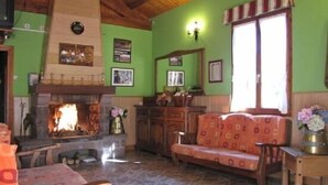 Una sala de estar acogedora con chimenea, paredes verdes, muebles de madera y una ventana con cortinas a rayas.