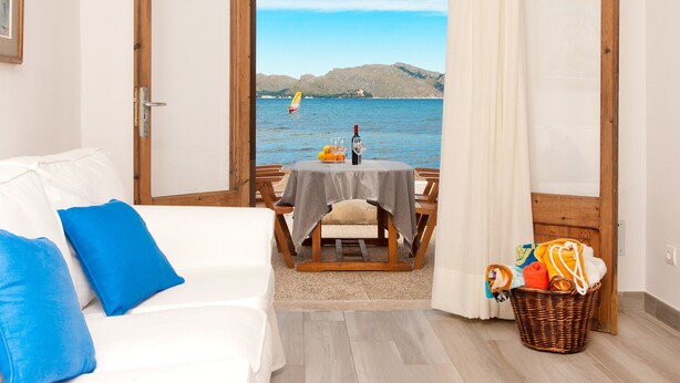 Ein Zimmer mit einer weißen Couch, einem Tisch mit Tischdecke und einem Korbwannenkorb mit Gegenständen.