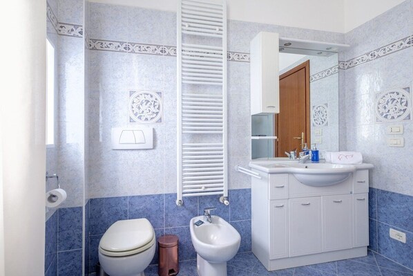 A bathroom with a toilet, bidet, and a sink with a mirror above it. - Ai Turchesi (Venezia)