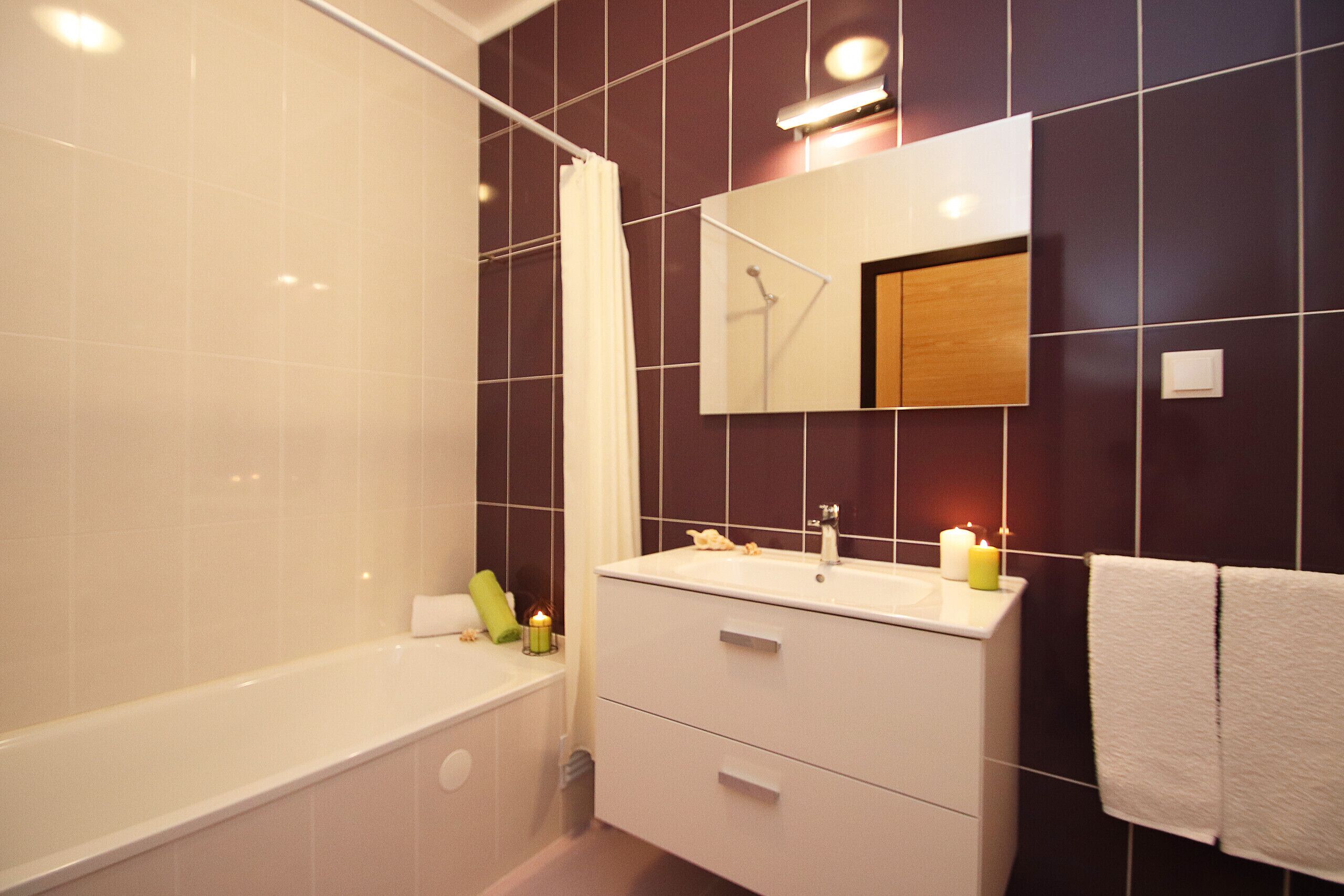 A modern bathroom with a bathtub, a sink, and a mirror.