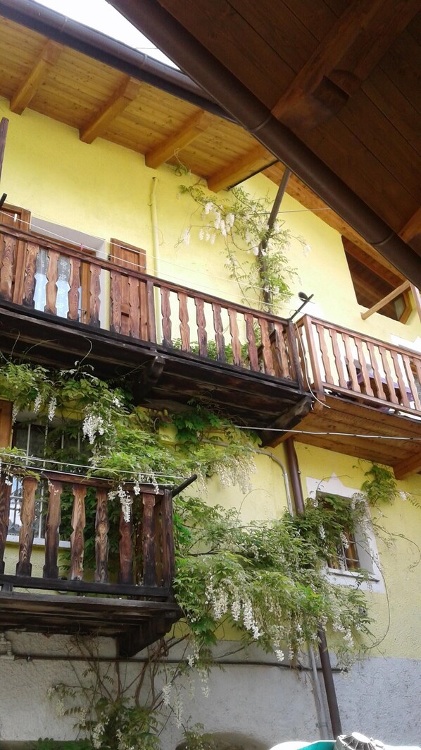 A building with a yellow exterior, wooden balconies, and climbing plants.