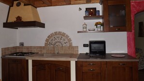Una cocina con armarios de madera, estufa a gas, microondas y salpicadero de azulejos.