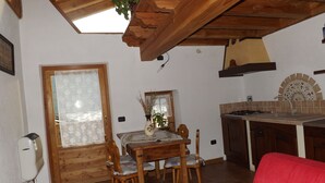 Una cocina acogedora con armarios de madera, una mesa de comedor con sillas, un sofá rojo y un tragaluz.