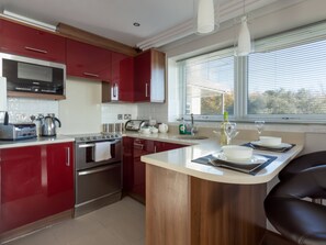 A modern kitchen with red cabinets, stainless steel appliances, and a central island.