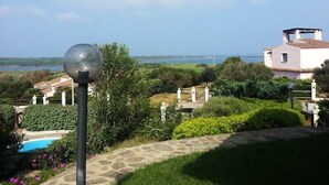 Un jardin avec une piscine, un lampadaire et une vue sur la mer et les bâtiments au loin.