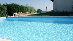 Une piscine aux eaux cristallines, avec une structure blanche et simple en arrière-plan.