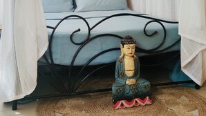 Una cama con dosel, una estatua de Buda y un tapete tejido.