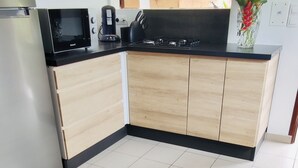 Una cocina moderna con microondas integrado, cafetera y estufa a gas.