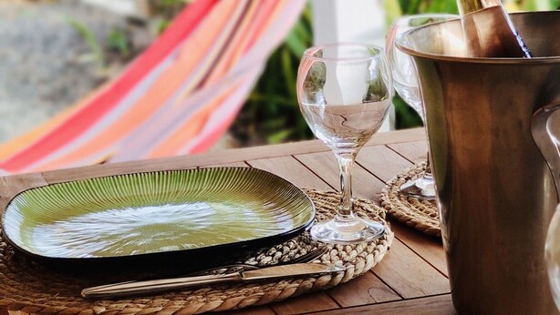 Una mesa de madera con dos platos, un vaso y un recipiente metálico.