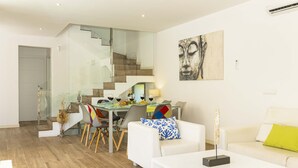 A modern living room with a dining area, white furniture, and a staircase. - Villa Jade I (Can Picafort)