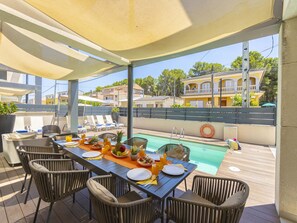 Ein Essbereich mit Blick auf den Pool, Gartenmöbel und ein für das Frühstück gedeckter Tisch.