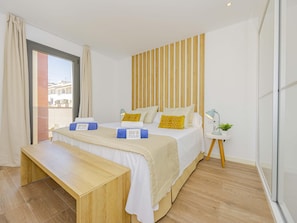 A hotel room with a bed, bedside table, and a small side table with a lamp and plant. - Villa Jade I· Villa with private pool in Can Picafort (Can Picafort)
