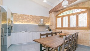 Une cuisine moderne avec des meubles blancs, un plan de travail en granit et une table à manger en bois, accompagnée de chaises.