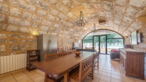 Cuina espaiosa amb un gran taula de fusta, parets de pedra i vista cap a l'exterior.