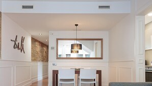 A modern dining area with a white table and chairs, a hanging pendant light, and a large mirror above the table. - Penthouse with private terrace in the heart of El Born (Barcelona)